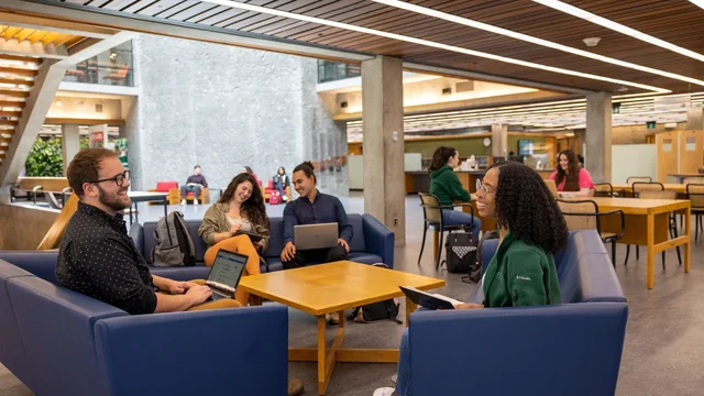 Trent students studying and talking together around a table in Bata Library