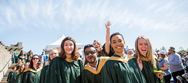 Graduates in Trent University gowns celebrating together outdoors